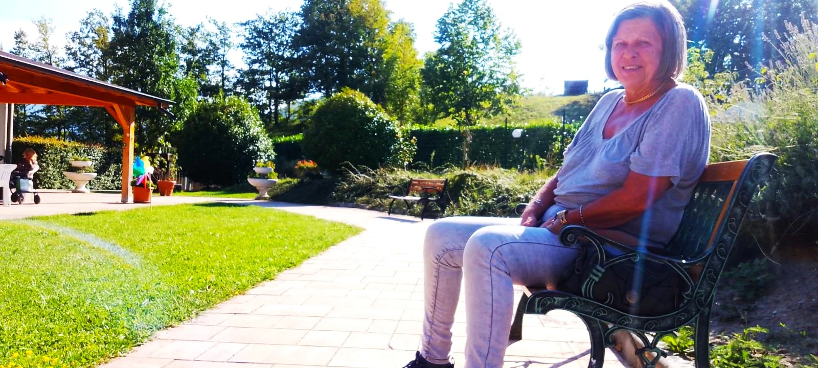 Una signora sorridente seduta su una panchina nel giardino